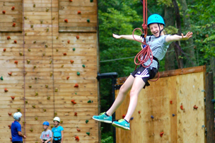 Young girl hanging by climbing walll.