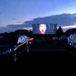 Movie playing on screen and parked cars at drive in movie