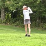 Woman swinging golf club
