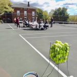 a bin of tennis balls with group of women in background