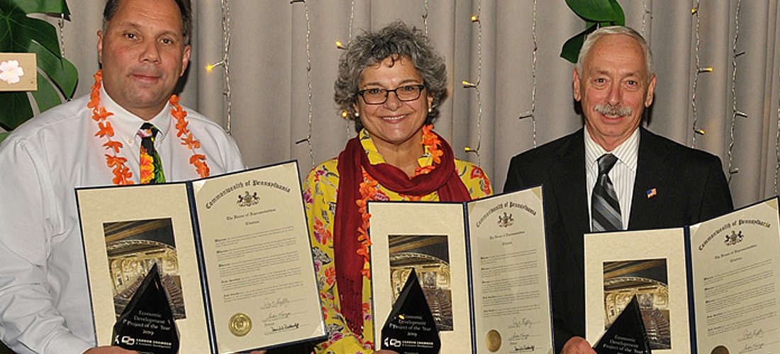Two men and one woman holding awards