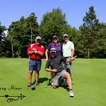 Three male golfers behind one male golfer kneeling on one knee