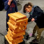 Young girl taking a piece from lifesized Jenga puzzle