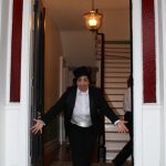 Woman with top hat and tails opening door