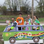 Group posing with hippie VW van prop