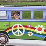 Boy peeking head inside window of hippie VW van prop