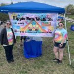 Two people standing near Hippie Run/Walk Banner