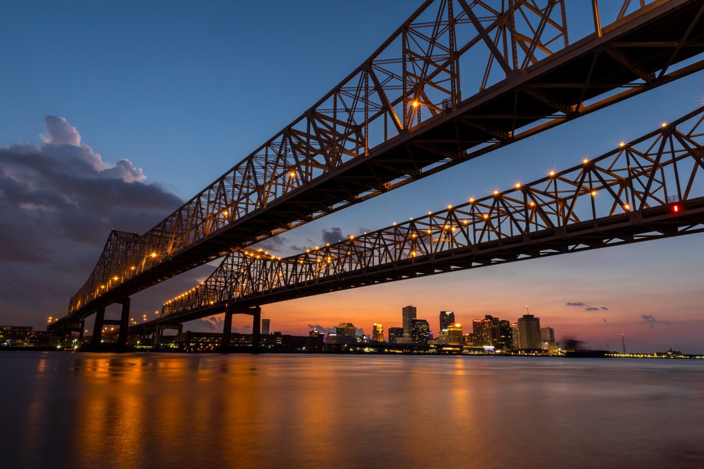 Crescent City Connection at sunset with New Orleans skyline in background. Click photo to learn about this major landmark, iconic to the New Orleans skyline.