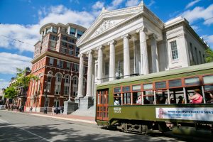 St. Charles Streetcar stopped on St. Charles Street in front of the Gallier Hall, a Greek Revival architectural style building.