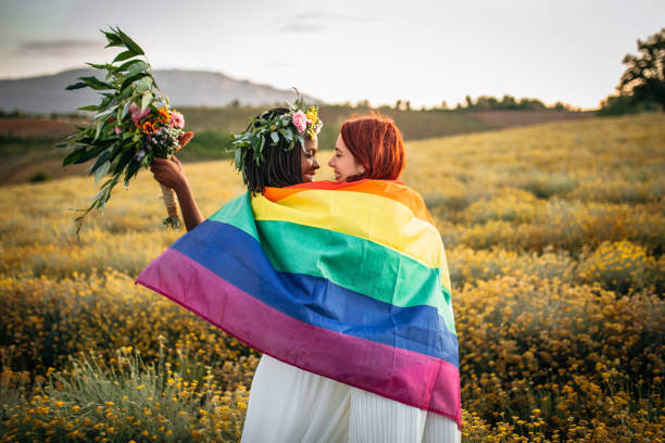 Two lesbian brides dancing covered with rainbow flag