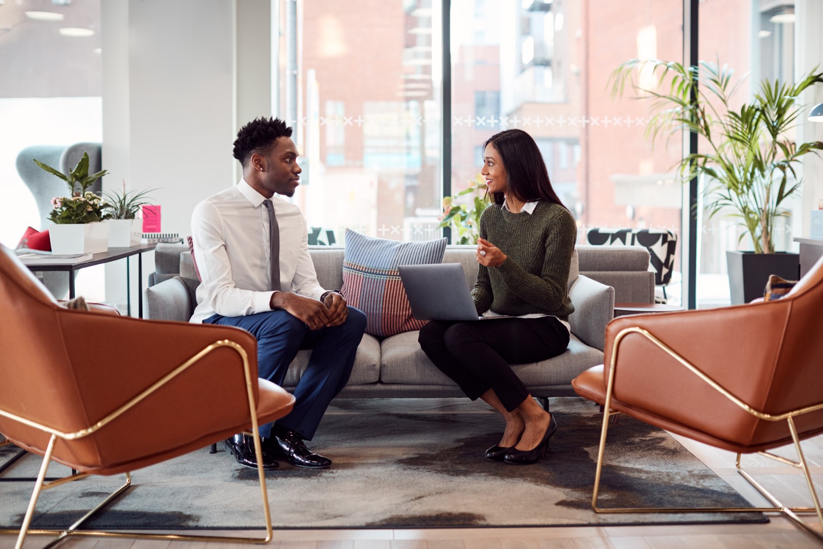 Businesswoman Interviewing Male Job Candidate In Seating Area Of Modern Office