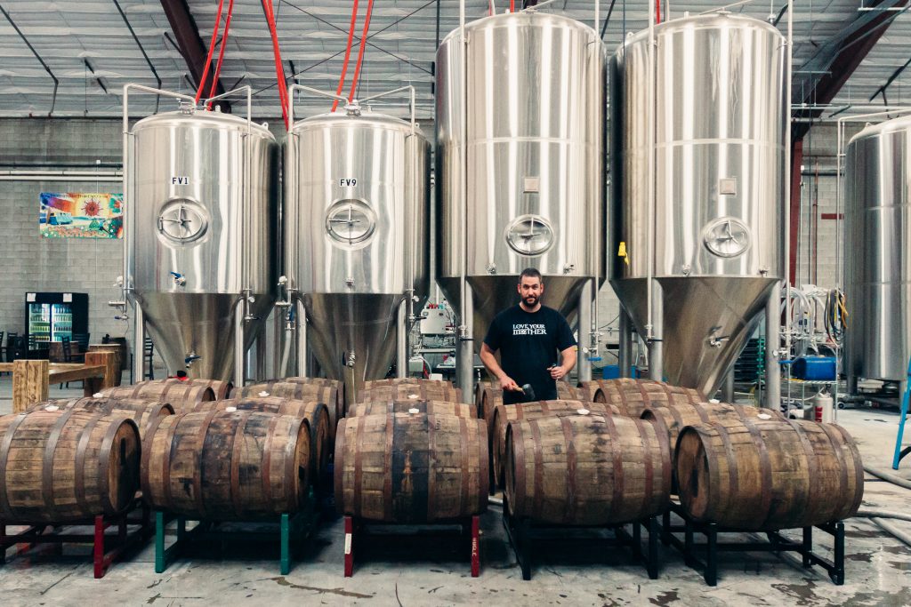 Man standing near barrels in a brewery