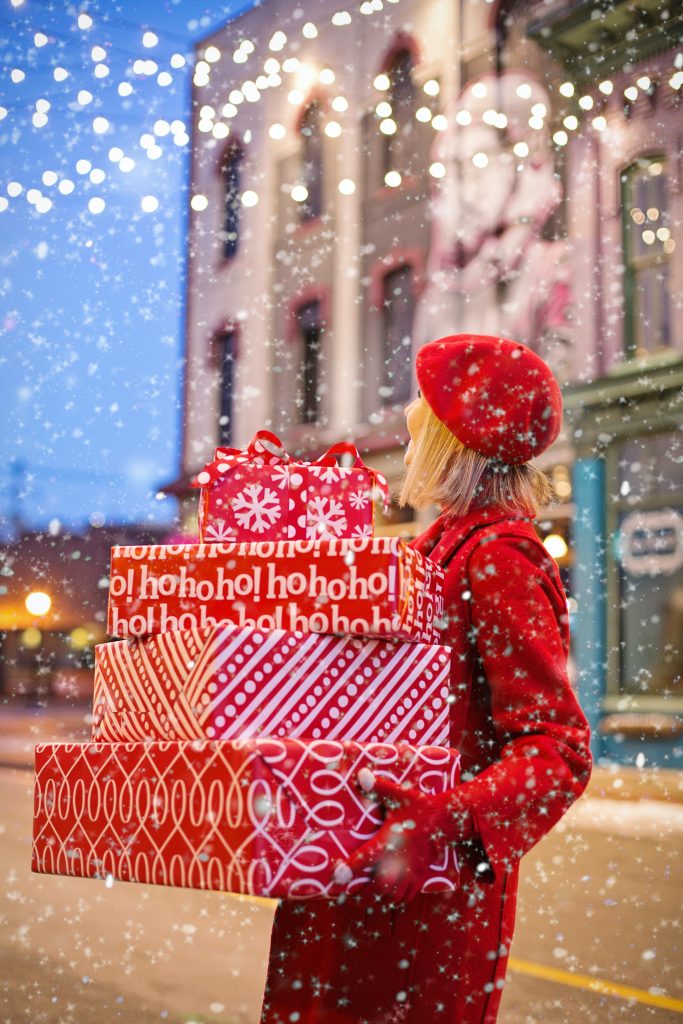 A woman standing outside holding Christmas presents