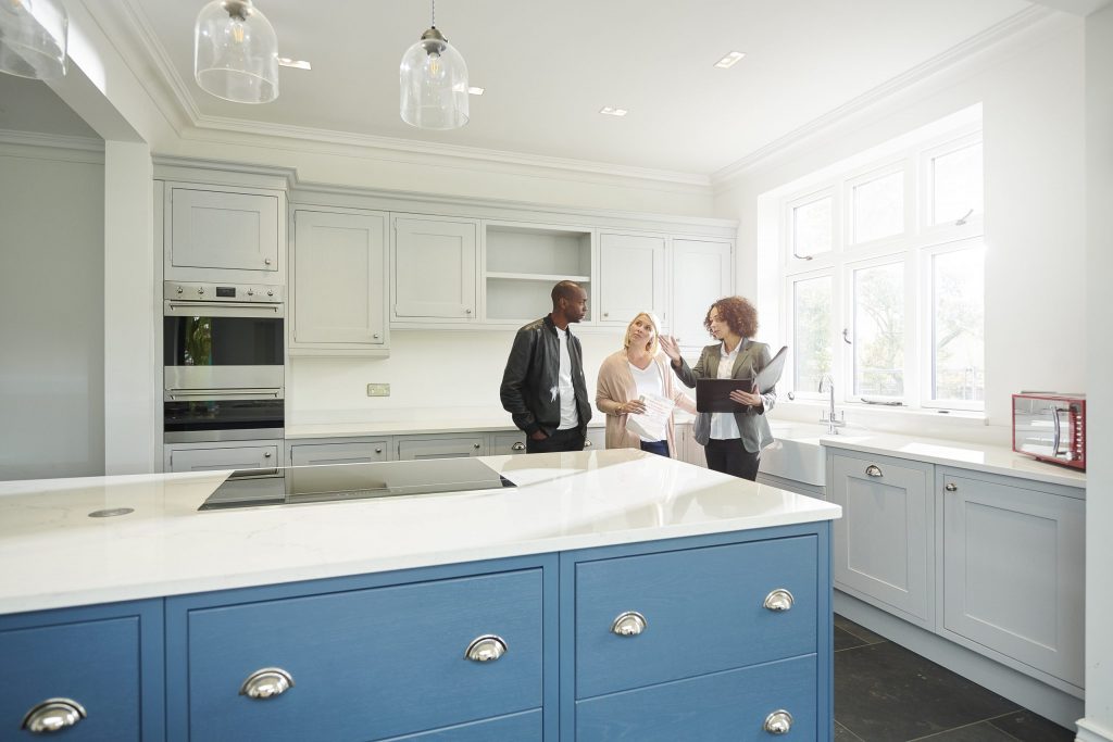 a saleswoman or estate agent shows a couple around a home with new kitchen