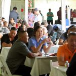 people at tables in discussions under outdoor tent
