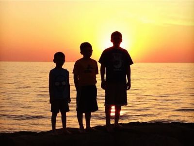 Shadows of 3 boys as the sun sets over lake erie