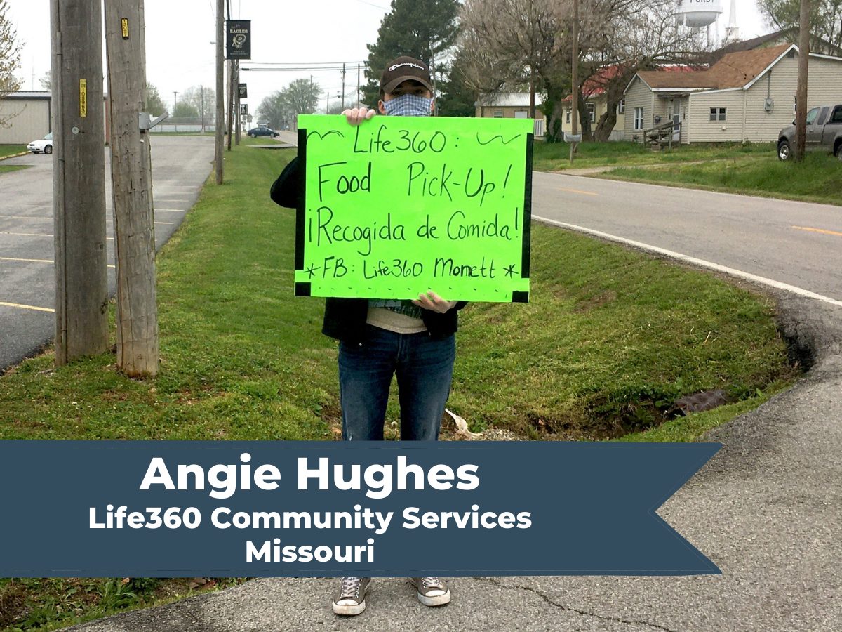 Staff person holds sign for Life360 promoting food distribution