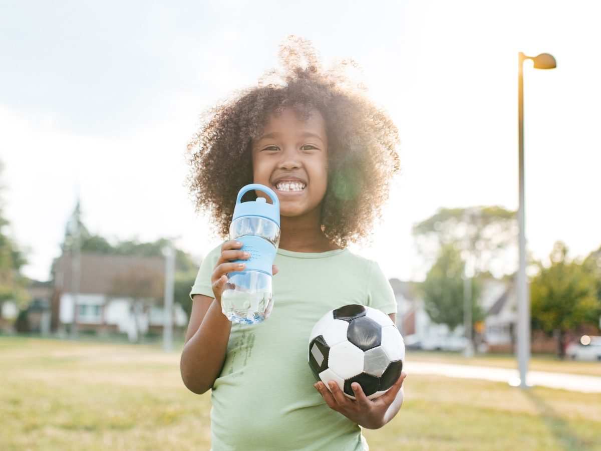 CACFP participant holds water bottle and soccer ball