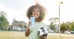 CACFP participant holds water bottle and soccer ball