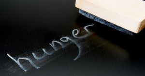 the word hunger written on a chalk board partially erased with an eraser nearby