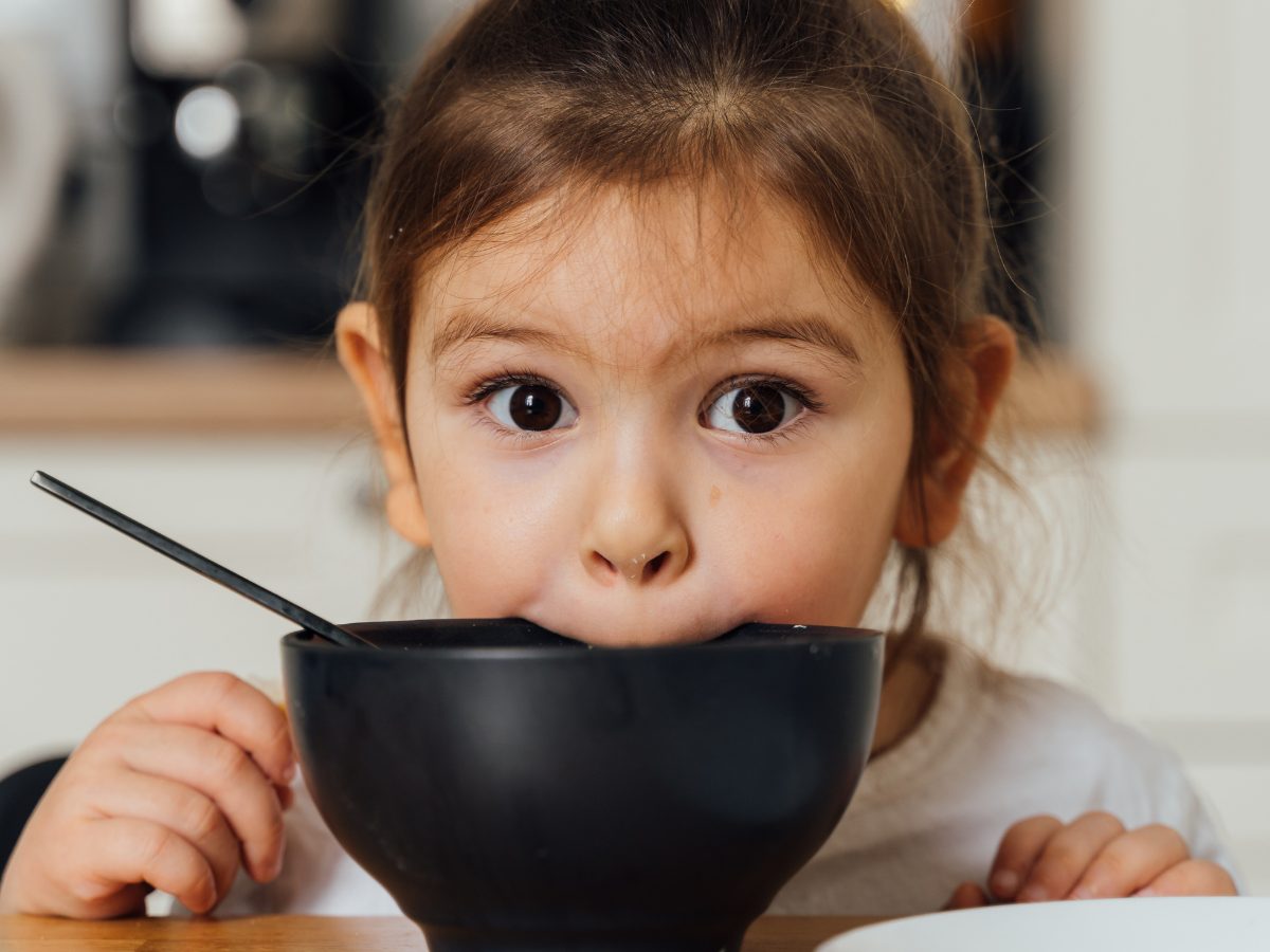 A girl leans forward over an empty bowl.