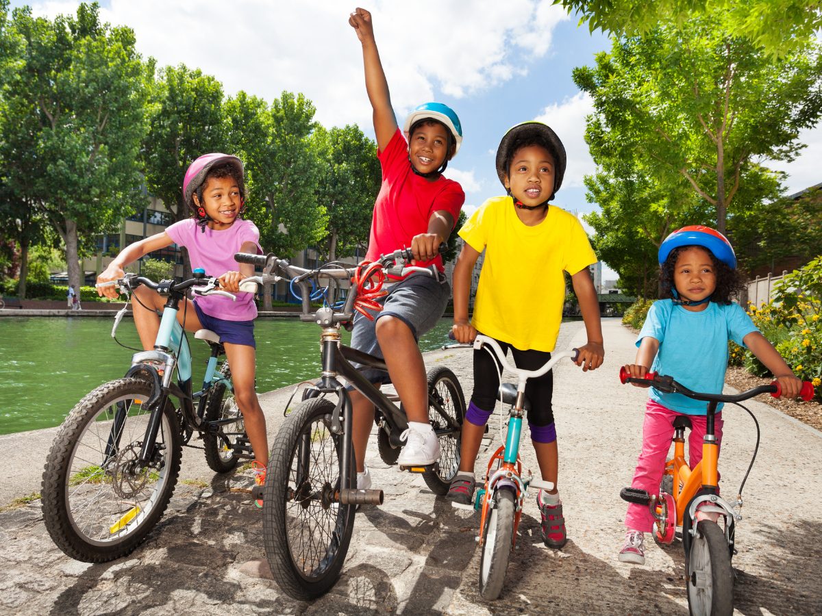 Four kids line up on bikes for a game of red-light green-light on wheels