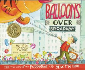 An image of the cover of the book Balloons over Broadway, in which a man is stringing along a giant hot air balloon down a New York street