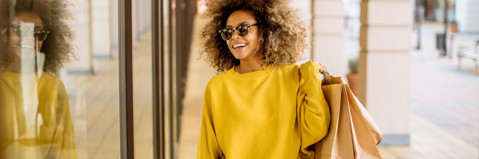 A young woman in a yellow top carrying shopping bags