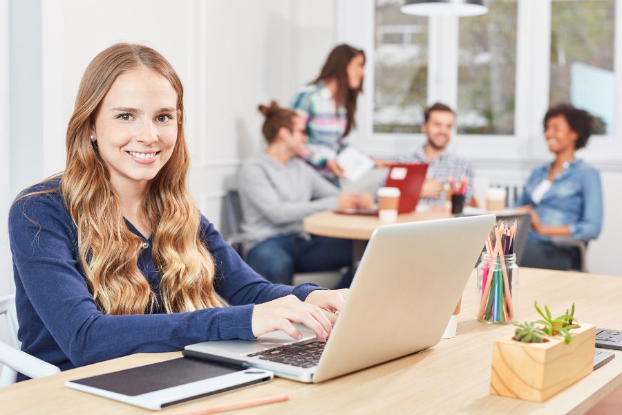 woman with blonde hair and blue shirt typing in a computer