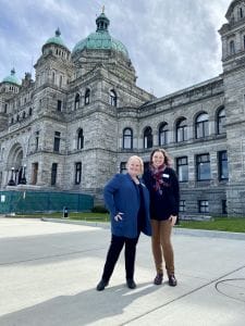 Jill McKnight and Lydia Elder standing in front of the Legislative buildings in Victoria, BC.