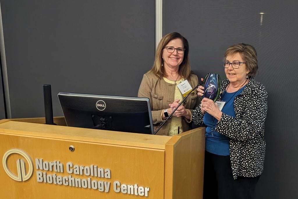 NCLifeSci President Laura Gunter presents a gift to Brenda Summers, who is retiring as the organization's director of workforce programs