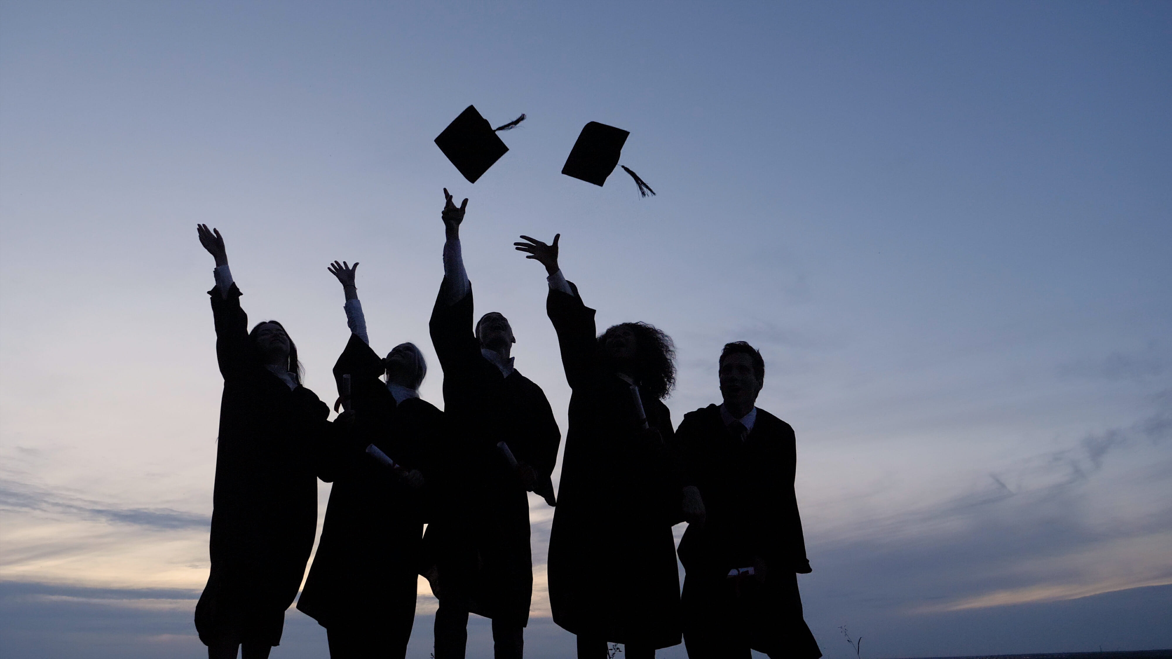 silhouette of students throwing graduation caps