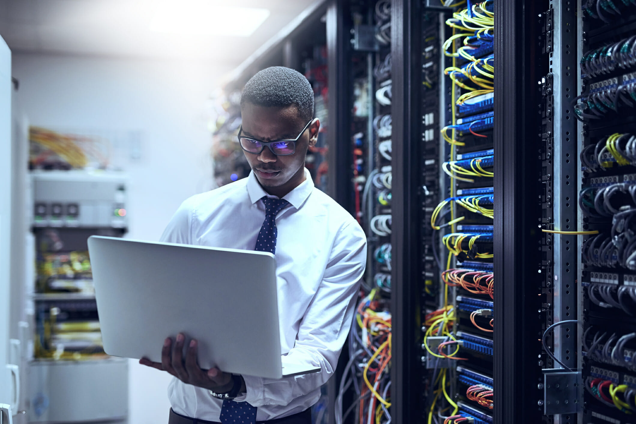 Young man works on a computer in server room