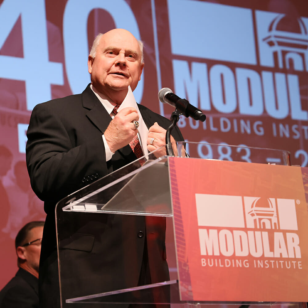 Roland Brown se dirige a la multitud en el World of Modular 2023 tras su ingreso en el Salón de la Fama de la industria de la construcción modular de MBI.