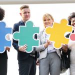 Photo of business people holding interlocking puzzle pieces