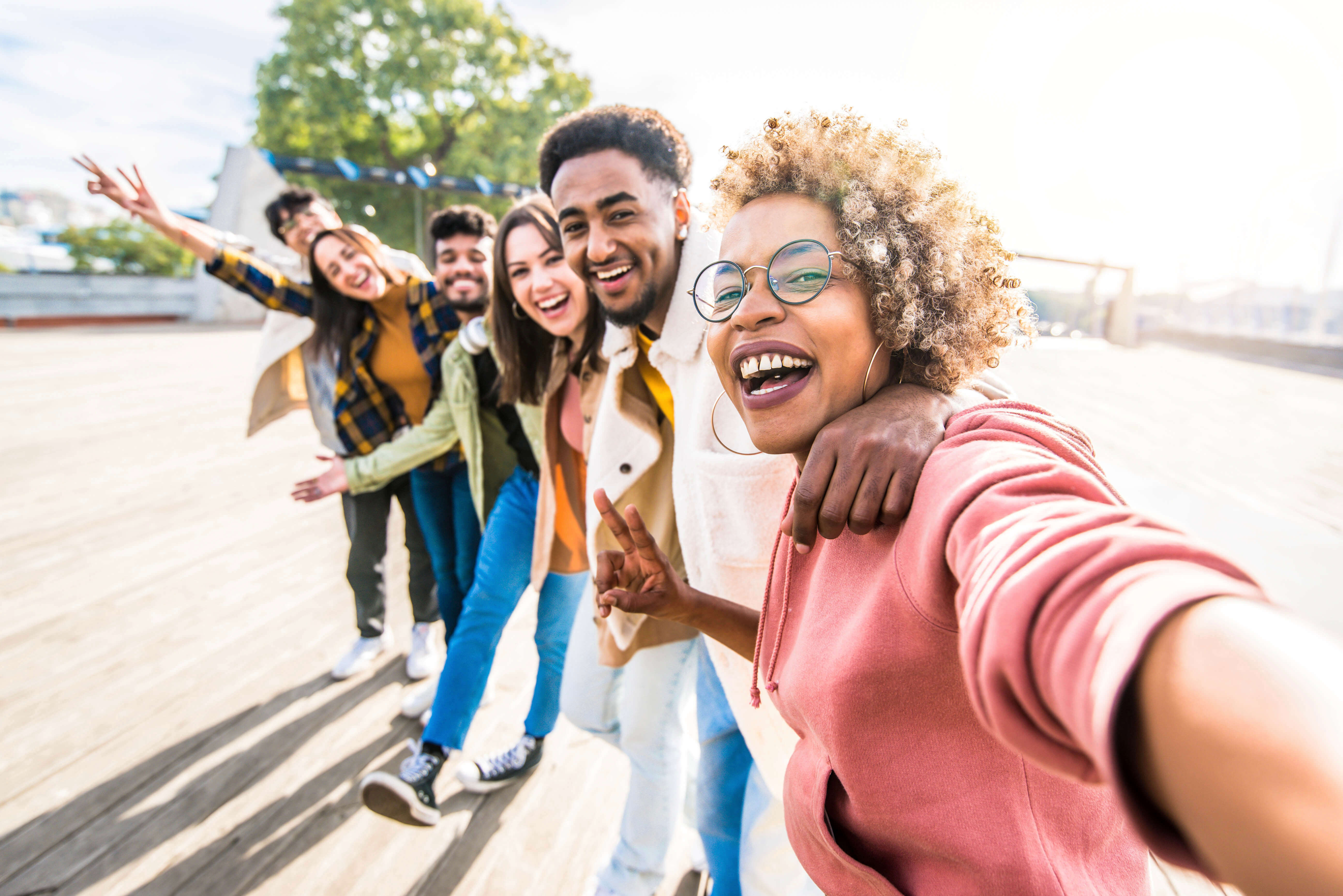 Multiracial friends group taking selfie pic with smartphone outside - Happy young people having fun walking on city street - Friendship concept with guys and girls enjoying summertime day outside. Representing FXBG Regional Black Tourism