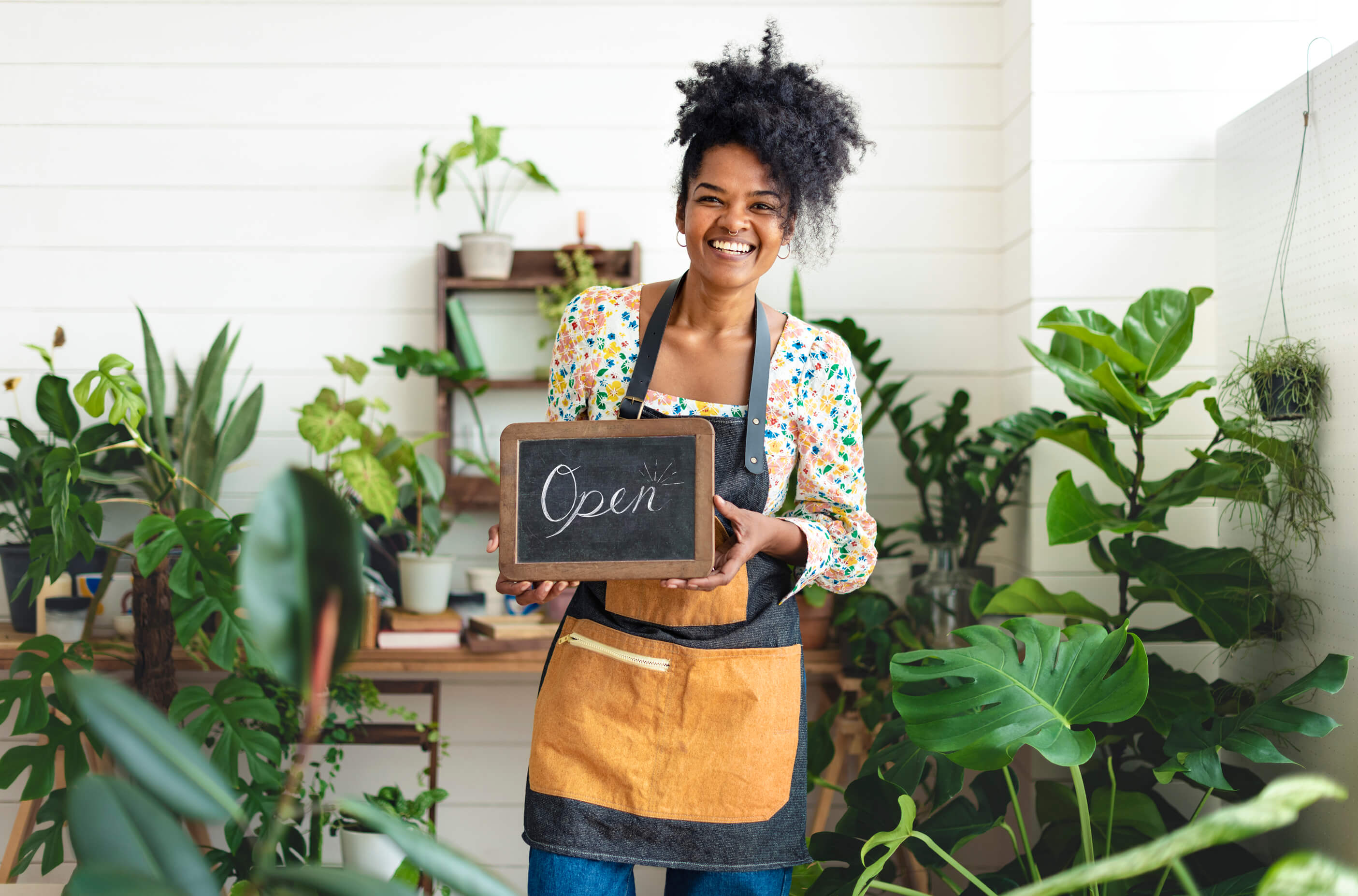 Plant shop owner holding open sign