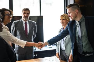 man and woman shaking hands over conference table