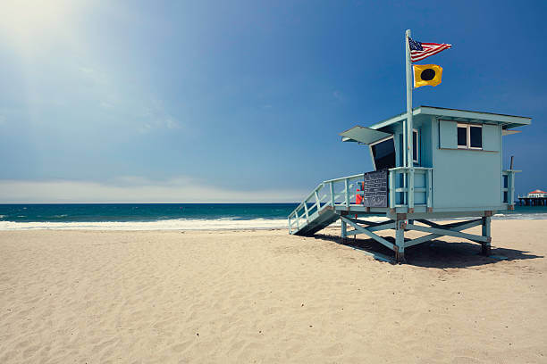 Lifeguard hut on Manhattan Beach, Los Angeles county. American and 'no surfing' flag blowing in the wind.