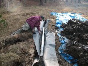 volunteer laying pipe in a trench