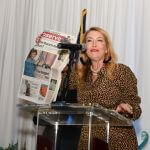 woman speaking holding up a newspaper