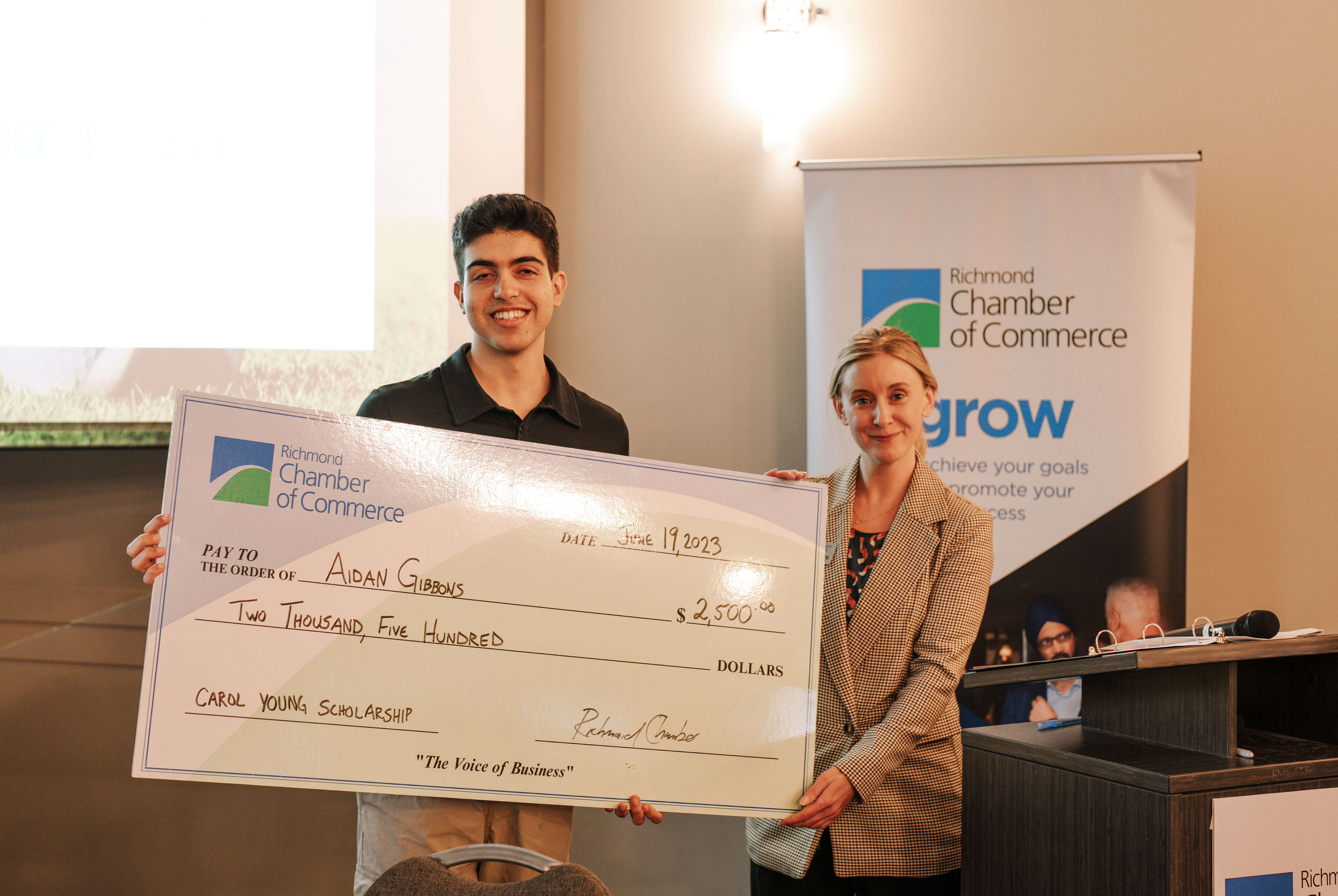 Aidan Gibbons (left), the Richmond Chamber of Commerce's 2023 Carol Young Scholarship Recipient, is
presented with a cheque by Shaena Furlong (right), President &amp; CEO, at the Chamber's 40th Annual Golf
Tournament