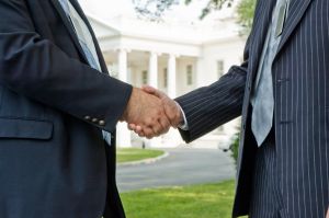 Two,Business,Men,Shaking,Hands,In,Front,Of,The,White
