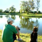 man and dog sitting by lake