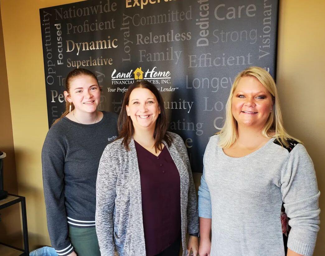 3 women in front of sign