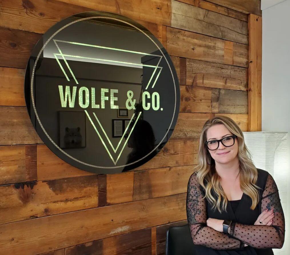 woman in front of wolfe & co sign