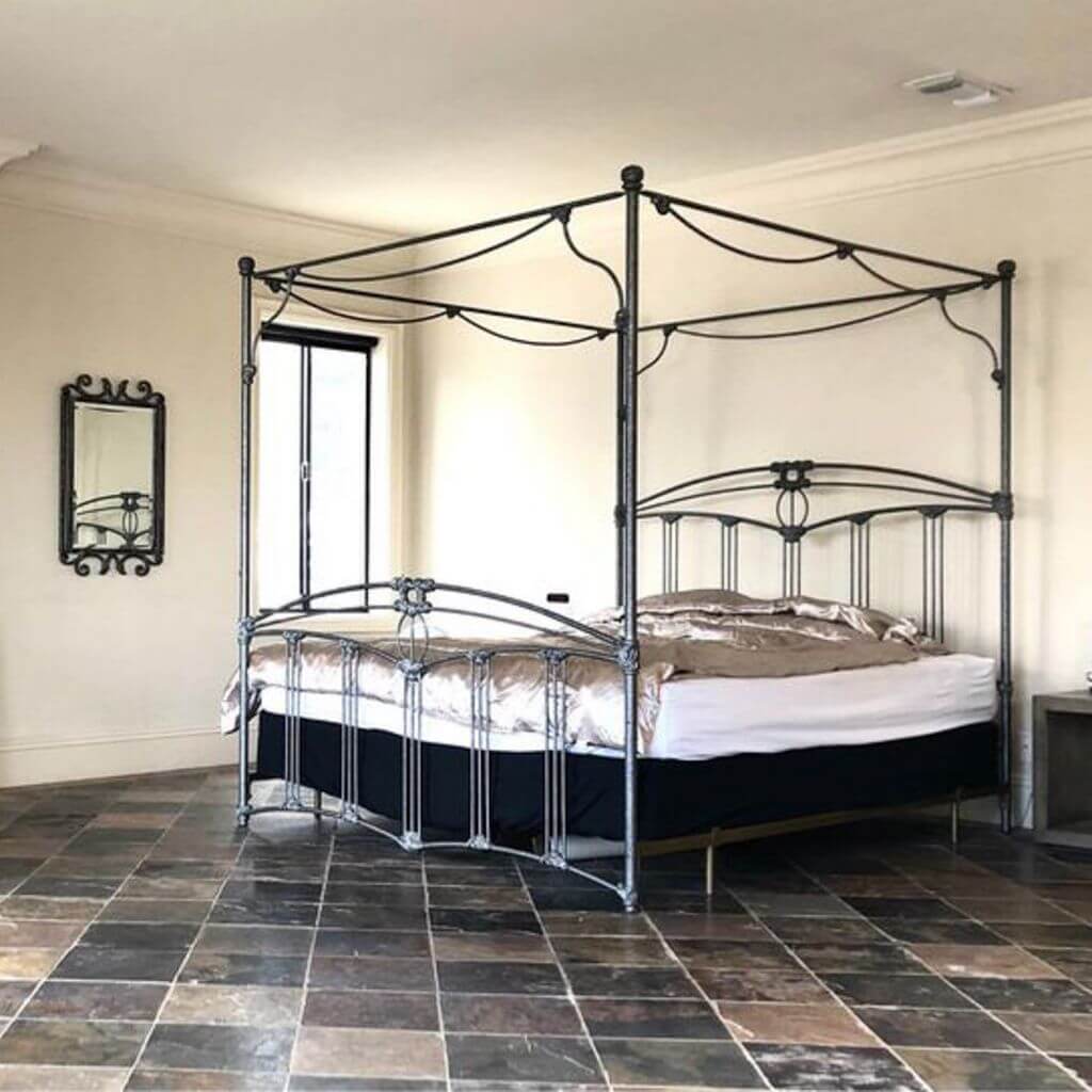 A four-poster bed on a tile floor