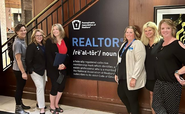 Realtors standing with a Realtor sign