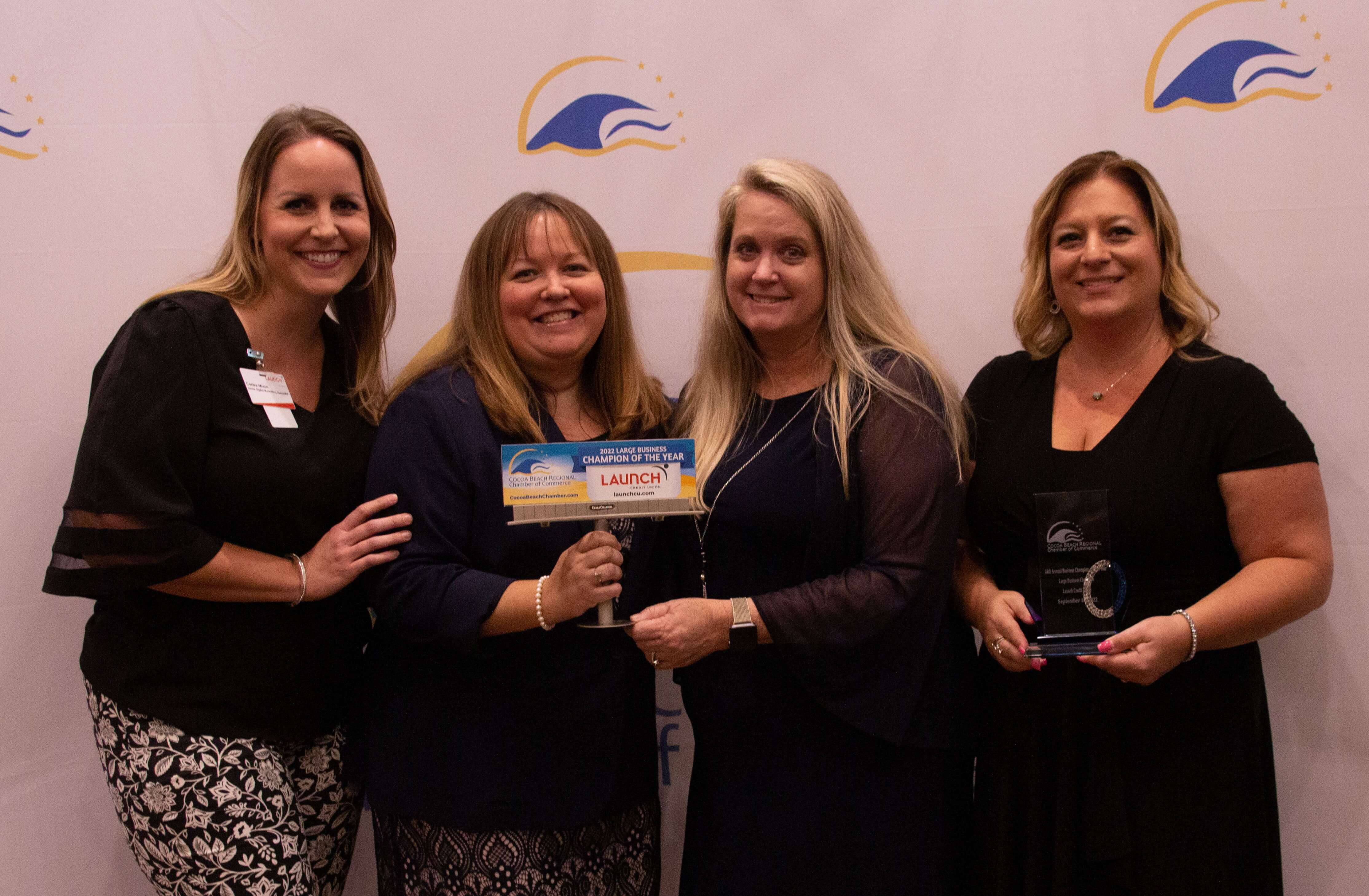 4 women holding a sign and award