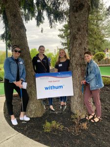 4 women in front of sponsor sign